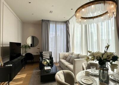 Modern living room with large windows, chandelier, and stylish furniture.