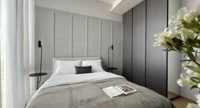 Modern bedroom with a bed, bedside tables, lamps, closet, and decorative flowers