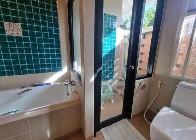 Modern bathroom with bathtub, shower, and green-tiled walls