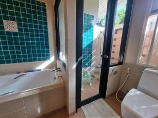 Modern bathroom with bathtub, shower, and green-tiled walls