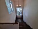 Interior staircase with large window and chandelier