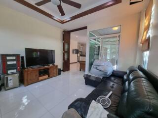 Modern living room with black leather sofa, TV, and open access to kitchen