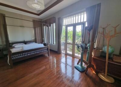 Bright and spacious bedroom with wooden floors, a bed, large windows, and balcony access.