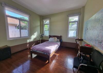 Spacious bedroom with wooden flooring and three large windows