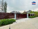 Exterior view of a gated property with a garden and trees