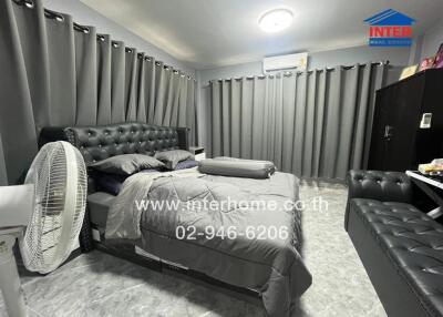 Cozy bedroom with a modern design, featuring a comfortable bed and grey furnishings.