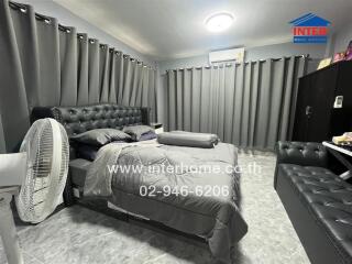 Cozy bedroom with a modern design, featuring a comfortable bed and grey furnishings.