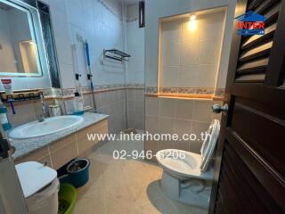 Bathroom with a sink, toilet, wall mirror, and storage rack.