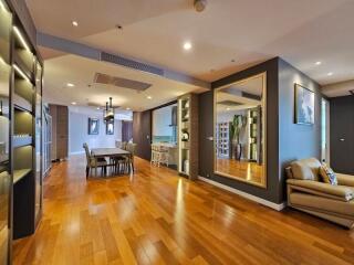 Spacious modern living area with wooden floors, large mirror, and contemporary furniture