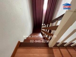 Staircase with wooden steps and white railing leading to the upper floor