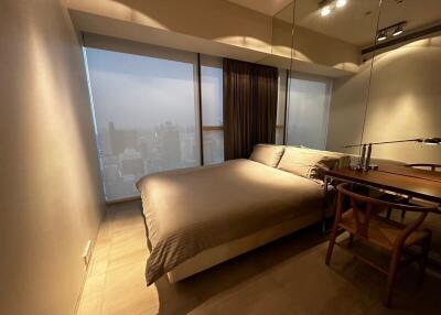 Bedroom with city view, large bed, and wooden desk