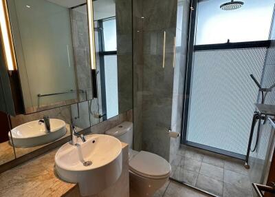 Modern bathroom with glass shower, marble countertops, and large mirror
