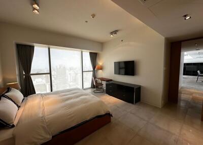 Spacious bedroom with a large window, modern decor, and a city view
