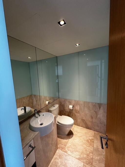 Modern bathroom with tiled flooring, a toilet, and a sink with a large mirror