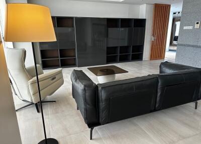 Modern living room with black leather sofa, armchair, and a floor lamp