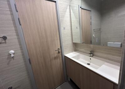 Modern bathroom with wooden door, large mirror, and sink