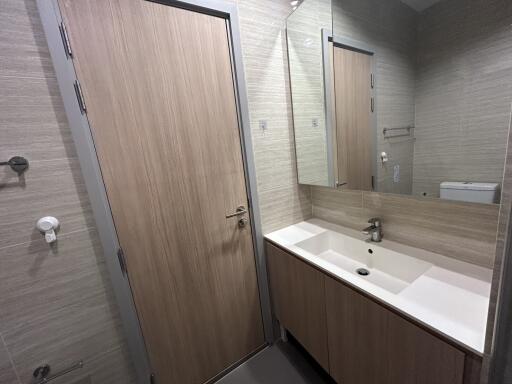 Modern bathroom with wooden door, large mirror, and sink