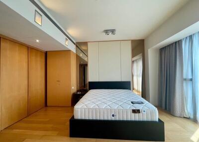 Modern bedroom with large bed, wooden flooring, built-in wardrobes, and large windows
