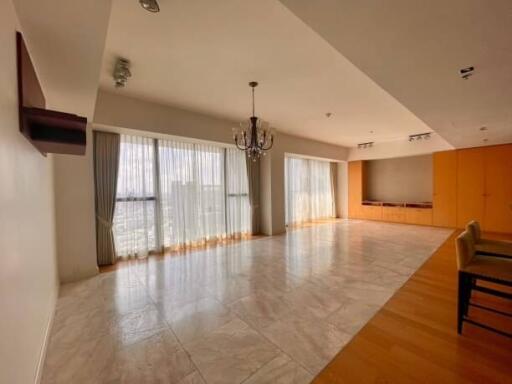 Spacious living room with curtain-clad windows, chandelier, and tiled floors