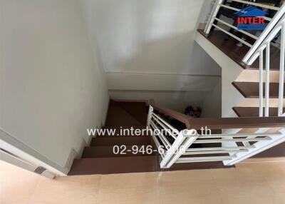 Indoor staircase with wooden steps and white railings leading down