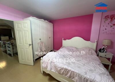 Bedroom with pink walls, white wardrobe, and double bed