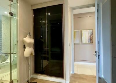 hallway with a mannequin, glass door, closet, and paintings
