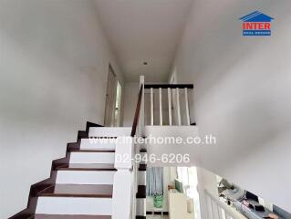 Indoor staircase with white railing and wooden steps