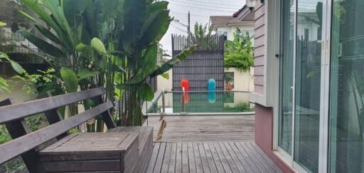 A patio with a wooden bench, greenery, pool, and modern architecture