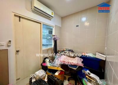 Cluttered storage or laundry room with tile walls and air conditioning unit