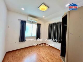 Empty bedroom with wooden floor, window, and air conditioning