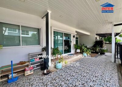 Covered outdoor area with tiled flooring and various potted plants