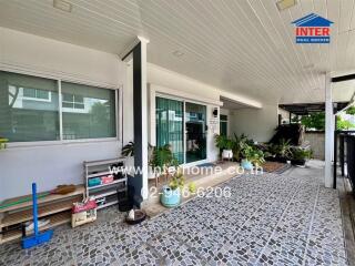 Covered outdoor area with tiled flooring and various potted plants