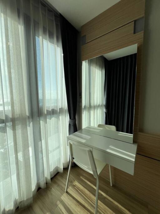 Bedroom with a desk and chair beside a large window with sheer curtains