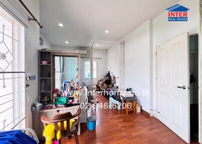 Bedroom with wooden floor, storage shelves, and various items