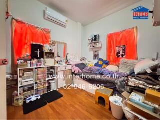 Cluttered bedroom with red curtains and a variety of personal items.