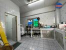 A well-equipped kitchen with tiled walls and floors, featuring countertops, sinks, cabinets, and appliances