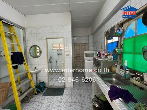 Spacious kitchen with large sink, storage shelves, and a washing machine