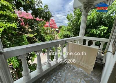 Balcony view with greenery and a towel hanging on railing