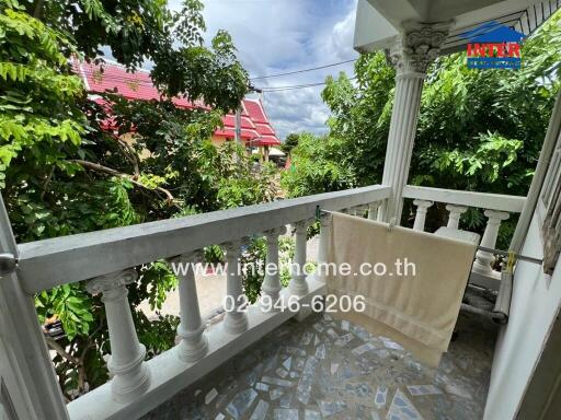 Balcony view with greenery and a towel hanging on railing