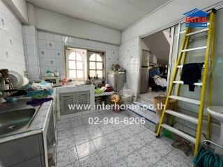 A kitchen with tiled walls and floors, featuring a sink, countertop, and storage cabinets