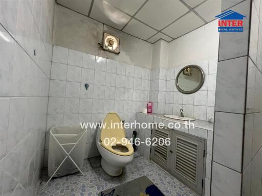Bathroom with white tiles, sink, mirror, and a toilet