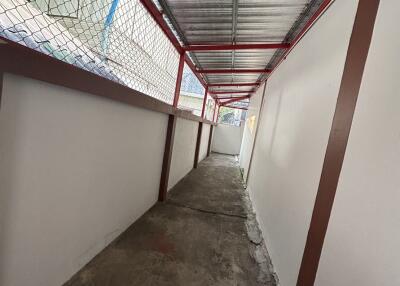 Long corridor with metal roof and chain-link fence on one side