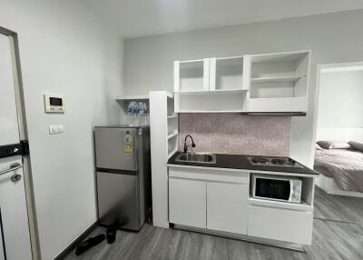 Modern compact kitchen with white cabinets, small sink, stove, and refrigerator