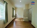 Bright bedroom with wooden flooring, green curtains, and a window allowing natural light.