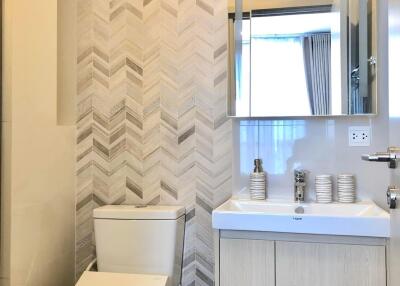 Modern bathroom with toilet and sink under mirror cabinet