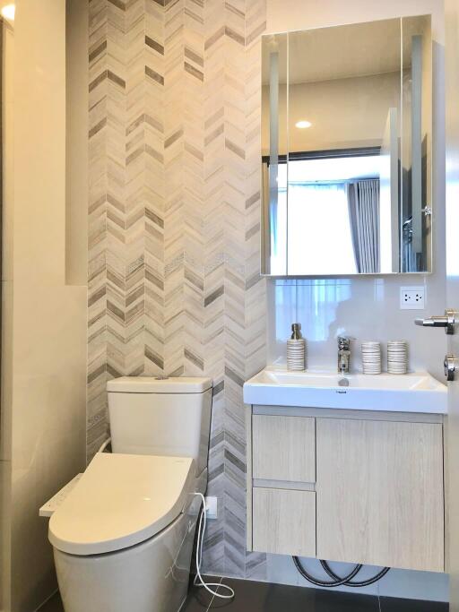 Modern bathroom with toilet and sink under mirror cabinet