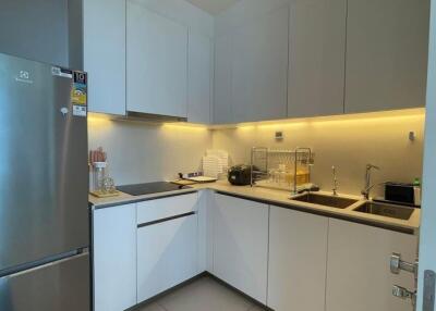 Modern kitchen with white cabinets, stainless steel fridge, and under-cabinet lighting