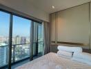 Spacious bedroom with large glass windows offering a panoramic city view