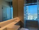 Modern bathroom with large mirror, glass shower, and city view