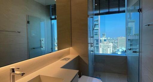 Modern bathroom with large mirror, glass shower, and city view